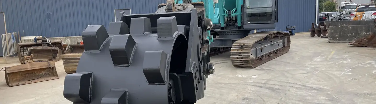 Compaction wheel attached to construction equipment, used for securing soil around newly installed safety barriers.