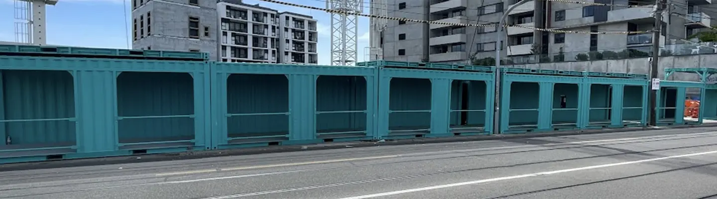 Covered container walkway at construction site, providing safe pedestrian access and separation from active work zones.