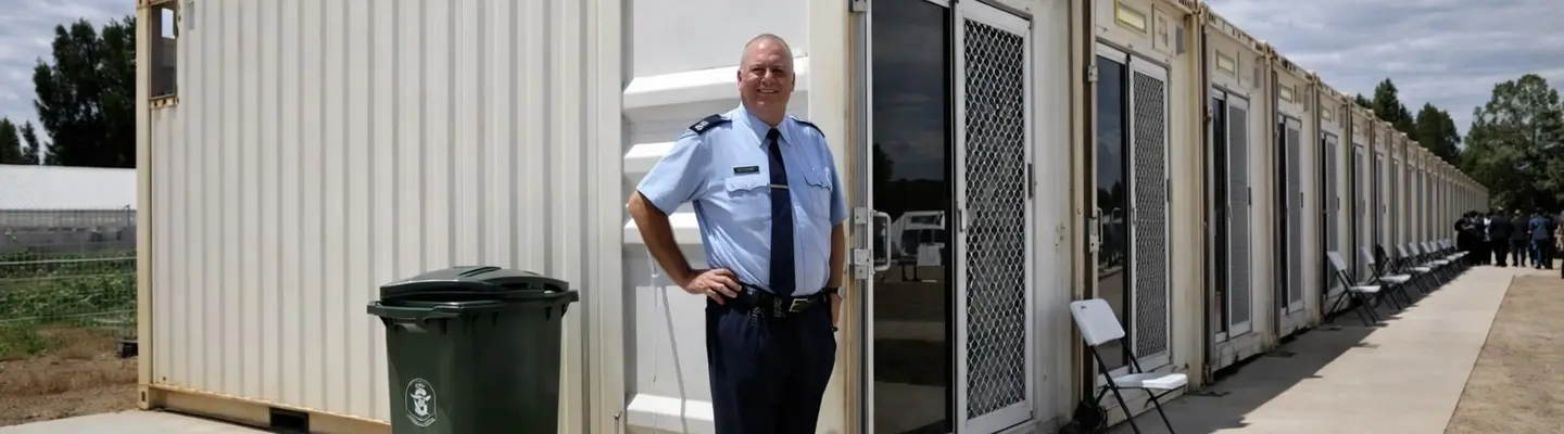 Man standing confidently in front of a modern containerized house, showcasing innovative modular living design.