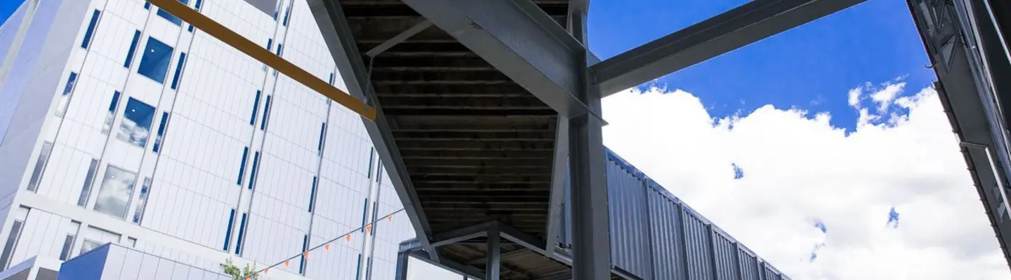 Covered hospital walkway made from long shipping containers, providing sheltered access between buildings for staff and patients.